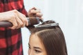 Hair stylist barber styling long hair with hair iron for beautiful young asian woman with cup of tea in beauty salon, working Royalty Free Stock Photo