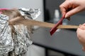 Hair stylist makes bouffant using comb on thin strands. Shatush technique for hair bleaching Royalty Free Stock Photo