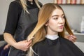 Hair stylist& x27;s hands doing professional hairstyling of female long hair in a beauty salon.