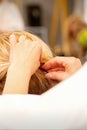 Hair stylist's hands doing professional hairstyling of female long hair in a beauty salon.