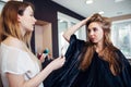 Hair stylist working on female customer s hairdo clipping strands with hair pins in hairdressing studio