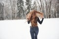 Hair to the different sides. Rear view of girl with long hair runs near the forest to the automobile in wintertime Royalty Free Stock Photo