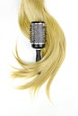 Hair tools, beauty and hairdressing concept - Round brush for styling hair with strand of blonde hair on white background. Round Royalty Free Stock Photo