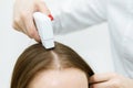 Hair treatment. Fragment of the head with the hair and the hand of the doctor trichologist. Treatment of the hair roots. Close-up