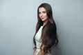 Haircare concept. Beautiful brunette woman with smooth straight healthy silky hair posing on grey background portrait