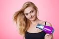 Haircare concept. Beautiful woman uses hair dryer, blows dry her hair, prepares for date with handsome boyfriend. Pretty young blo Royalty Free Stock Photo