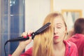 Woman straightening her long blond hair Royalty Free Stock Photo