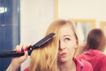 Woman straightening her long blond hair Royalty Free Stock Photo