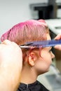 Haircut of dyed short pink wet hair of young caucasian woman by a male hairdresser in a barbershop. Royalty Free Stock Photo