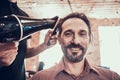 After a haircut, a man combs and dries his hair.