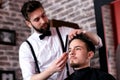 Hairdresser adjusts hair a customer with a comb Royalty Free Stock Photo
