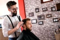 Hairdresser adjusts hair a customer with a comb Royalty Free Stock Photo