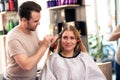 Hairdresser applying color client at salon, doing hair dye