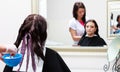 Hairdresser applying color female customer at salon, doing hair dye