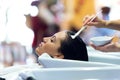 The hairdresser applying hair treatment for customer in a beauty salon.