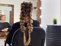 Hairdresser braiding woman`s hair in hairdressing salon Royalty Free Stock Photo