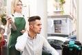 Hairdresser and client evaluate result after haircut. Stylist doing hair styling for guy Royalty Free Stock Photo