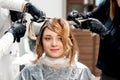 Hairdresser`s hands coloring hair of woman