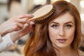 Hairdresser combing her long, red hair of his client in the beauty salon. Royalty Free Stock Photo