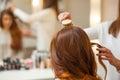 Hairdresser combing her long, red hair of his client in the beauty salon. Royalty Free Stock Photo