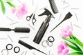 Hairdresser concept with spray, scissors, combs, barrette and tulips flowers on white background. Beauty concept. Flat lay, top vi