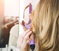Hairdresser curling blonde woman hair with electric iron curler tong Royalty Free Stock Photo