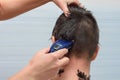 Hairdresser cut half the hair on the back of the head of a man at home