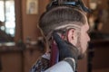 A hairdresser cuts a bearded young guy with a hair trimmer, combing the hair on his head. Work of the master in men`s haircut in Royalty Free Stock Photo