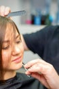 The hairdresser cuts the hair of a brunette woman. Hairstylist is cutting the hair of female client in a professional Royalty Free Stock Photo