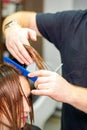 The hairdresser cuts the hair of a brunette woman. Hairstylist is cutting the hair of female client in a professional Royalty Free Stock Photo