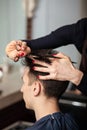 Hairdresser cutting man`s hair with scissors