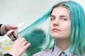 Hairdresser cutting with scissors long green hair of young woman. Hair care in beauty salon Royalty Free Stock Photo