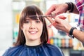 Hairdresser cutting woman bangs hair in shop