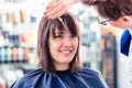 Hairdresser cutting woman hair in shop