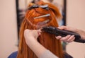 The hairdresser does hair extensions to a young, red-haired girl Royalty Free Stock Photo