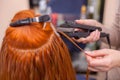 The hairdresser does hair extensions to a young, red-haired girl Royalty Free Stock Photo