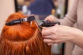 The hairdresser does hair extensions to a young, red-haired girl, in a beauty salon. Royalty Free Stock Photo