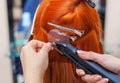 The hairdresser does hair extensions to a young, red-haired girl, in a beauty salon Royalty Free Stock Photo