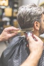 Side view of professional barber styling hair of his client by using comb and clipper Royalty Free Stock Photo