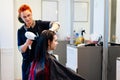 Hairdresser drying female customer hair with hand dryer in hair salon