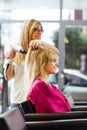 Hairdresser drying female customer`s hair in beauty salon.