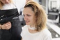 Hairdresser drying hair with hairdryer to woman in barber shop Royalty Free Stock Photo