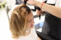 Hairdresser drying hair with hairdryer to woman client in beauty salon Royalty Free Stock Photo