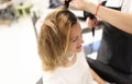 Hairdresser drying hair with hairdryer to woman client in beauty salon Royalty Free Stock Photo