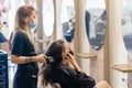 Hairdresser drying her client& x27;s hair with a hairdryer wearing protective masks in a beauty centre. Royalty Free Stock Photo