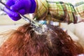 The hairdresser dyes his client`s hair in beauty salon