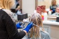 Hairdresser is dying female hair. Hands in glives with brush, coloring in hair salon. Royalty Free Stock Photo