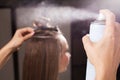 Hairdresser fixing a topknot of a woman with a hair spray