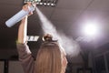 Hairdresser fixing a topknot of a model with a hair spray