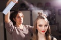 Hairdresser fixing an unusual bun with a hair spray Royalty Free Stock Photo